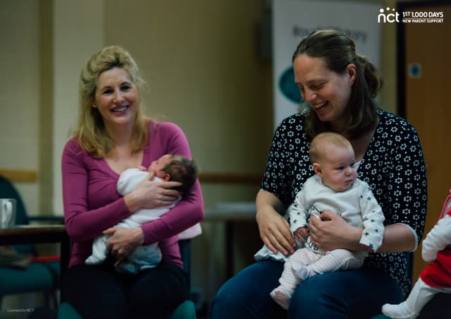 two mums smiling with their babies